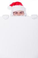 Merry Christmas Santa Claus looking out of the copy space while being isolated on white photo