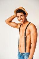 Young and free. Handsome young Afro-American hipster holding his hand on the hat and smiling while standing against grey background photo