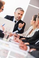 Business meeting. Business people in formalwear discussing something while sitting together at the table photo