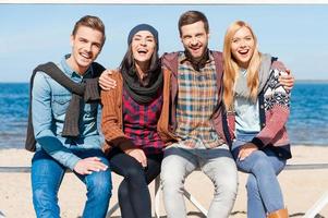 Friends forever. Group of young happy people bonding to each other and smiling while sitting at the riverbank photo