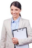 Beauty at work. Side view of confident young women holding clipboard while standing against white background photo