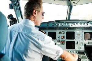 Ready to take off. Rear view of confident male pilot sitting in cockpit and getting an airplane ready to flight photo