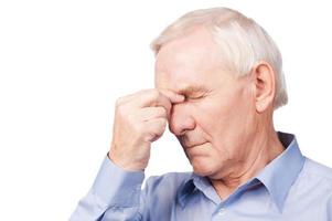 This pain torturing me Frustrated senior man in shirt holding hand on his head and keeping eyes closed while standing against white background photo