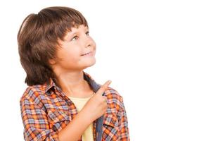 Showing the right direction. Cheerful little boy pointing away while standing isolated on white photo