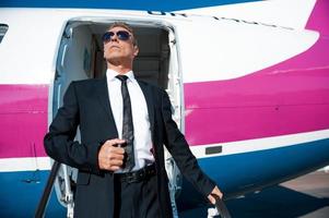 Boss is here. Low angle view of confident mature businessman getting out of airplane and looking away photo
