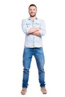 Confident handsome. Full length of handsome young man in casual wear keeping arms crossed and smiling while standing isolated on white background photo