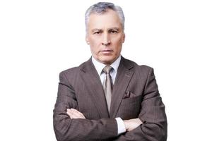 Successful businessman. Portrait of confident mature man in formalwear looking at camera while keeping arms crossed and standing against white background photo