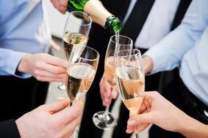 Celebrating great success. Close-up of business people holding flutes with champagne and toasting photo