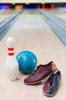 todo lo que necesitas para jugar a los bolos. primer plano de zapatos de bolos, bola azul y alfiler en una bolera foto