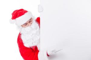 Just look at that. Traditional Santa Claus pointing copy space while standing against white background photo