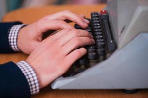 autor en la máquina de escribir. primer plano del hombre escribiendo algo en la máquina de escribir foto