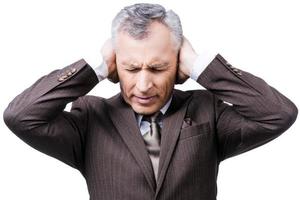 This is too loud Frustrated mature man in formalwear holding head in hands and keeping eyes closed while standing against white background photo