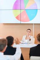 Your opinion is important for us. Confident young woman in formalwear giving a word to someone from audience while sitting in conference hall photo