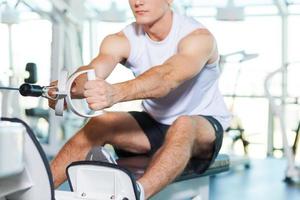 Working out in gym. Cropped image of concentrated young man working out in gym photo