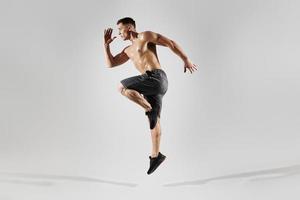 Confident muscular man with perfect body jumping against white background photo