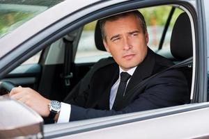 Driving his new car. Confident mature businessman driving car and looking away photo