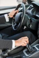 Driving a new car. Close-up of man in formalwear driving car photo