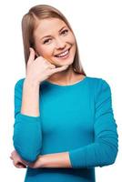 Call me Cheerful young women gesturing phone sign and smiling while standing against white background photo