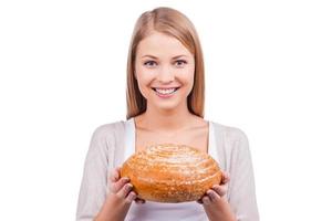 pan recién cocido. hermosa mujer joven sosteniendo pan y sonriendo mientras está de pie contra el fondo blanco foto