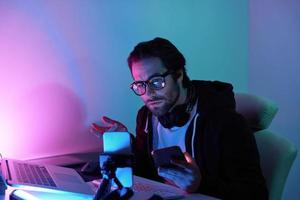 Concentrated young man using computer and streaming online against colorful background photo