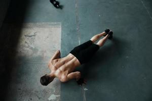 vista superior de un joven musculoso haciendo ejercicios de flexiones en el gimnasio foto