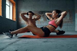 Confident fit couple exercising on exercise mats in gym together photo