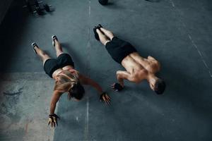 Top view of young fit couple doing push-ups in gym together photo