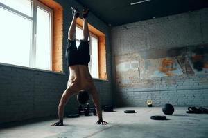 longitud completa de un joven en forma haciendo el pino mientras hace ejercicio en el gimnasio foto