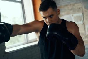 Concentrated young man practicing in punching while standing in gym photo