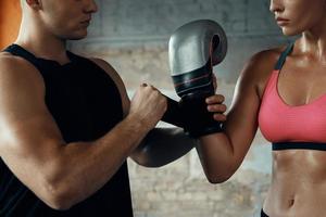 primer plano de un entrenador masculino que ayuda a una joven a usar guantes de boxeo en el gimnasio foto