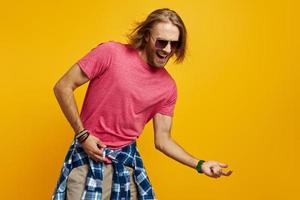 Handsome young man gesturing guitar and smiling while standing against yellow background photo