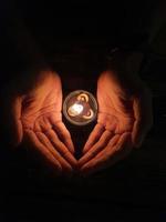 Cupped hands with burning candle. photo