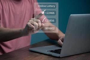 hombre que usa un teléfono inteligente y toca la pantalla virtual de lotería en línea para comprar dos juegos de números. foto