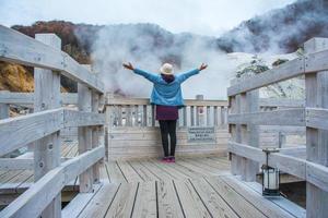 mujer de pie en jigokudani o valle del infierno en la ciudad de noboribetsu onsen, respiraderos de vapor caliente, arroyos sulfurosos y otra actividad volcánica, aguas termales, hokkaido, japón, concepto de viaje.