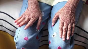 Feminine hands with ornate henna design rest on embroidered jeans video