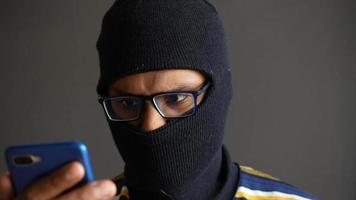 vuxen man i svart åka skidor mask och glasögon ser på smart telefon enhet video