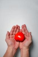 Hands holding and giving red heart for love, health care, organ donation, world heart day, world health day, mindfulness, well being, family insurance concept, copy space. photo