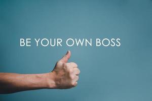BE YOUR OWN BOSS written word with hand thumps up and copy space. photo