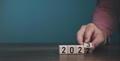 Wooden cube block flipping countdown from 2022 to 2023 on blue background, preparation for merry Christmas and happy new year concept. photo