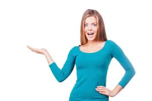 Excited about... Beautiful young woman holding copy space and looking surprised while standing against white background photo