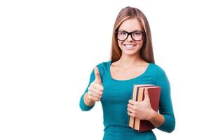 Studying is cool. Beautiful young women looking at camera and showing her thumb up while standing against white background photo