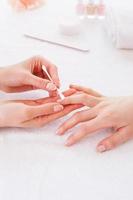 Preparing nails for manicure. Close-up of beautician cleaning nails of female customer photo