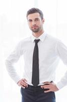 Young and successful. Confident young businessman in suit keeping arms crossed and smiling photo