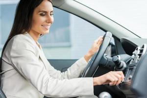 Driving with comfort. Side view of beautiful young man in formalwear driving car and touching dashboard with finger photo