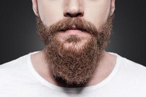 barba perfecta. primer plano, de, joven, barbudo, hombre estar de pie, contra, fondo gris foto