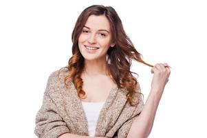 Curly beauty. Beautiful young smiling woman looking at camera and smiling while touching her curly hair and standing isolated on white photo