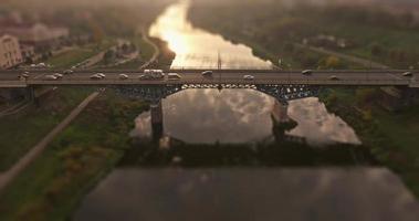 Zeitraffer mit Tilt-Shift-Effekt auf Luftaufnahme einer Straßenkreuzung mit starkem Verkehr auf einer riesigen Brücke über den Fluss am Abend video