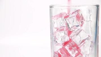 Soft drinks are poured over ice cubes in a clear glass, foaming and dispersing. video