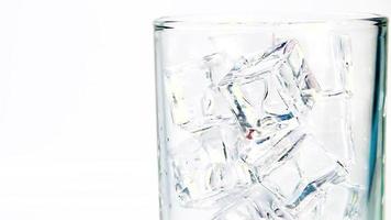 Soft drinks are poured over ice cubes in a clear glass, foaming and dispersing. video