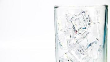 Erfrischungsgetränke werden in einem klaren Glas über Eiswürfel gegossen, schäumen und verteilen sich. video
